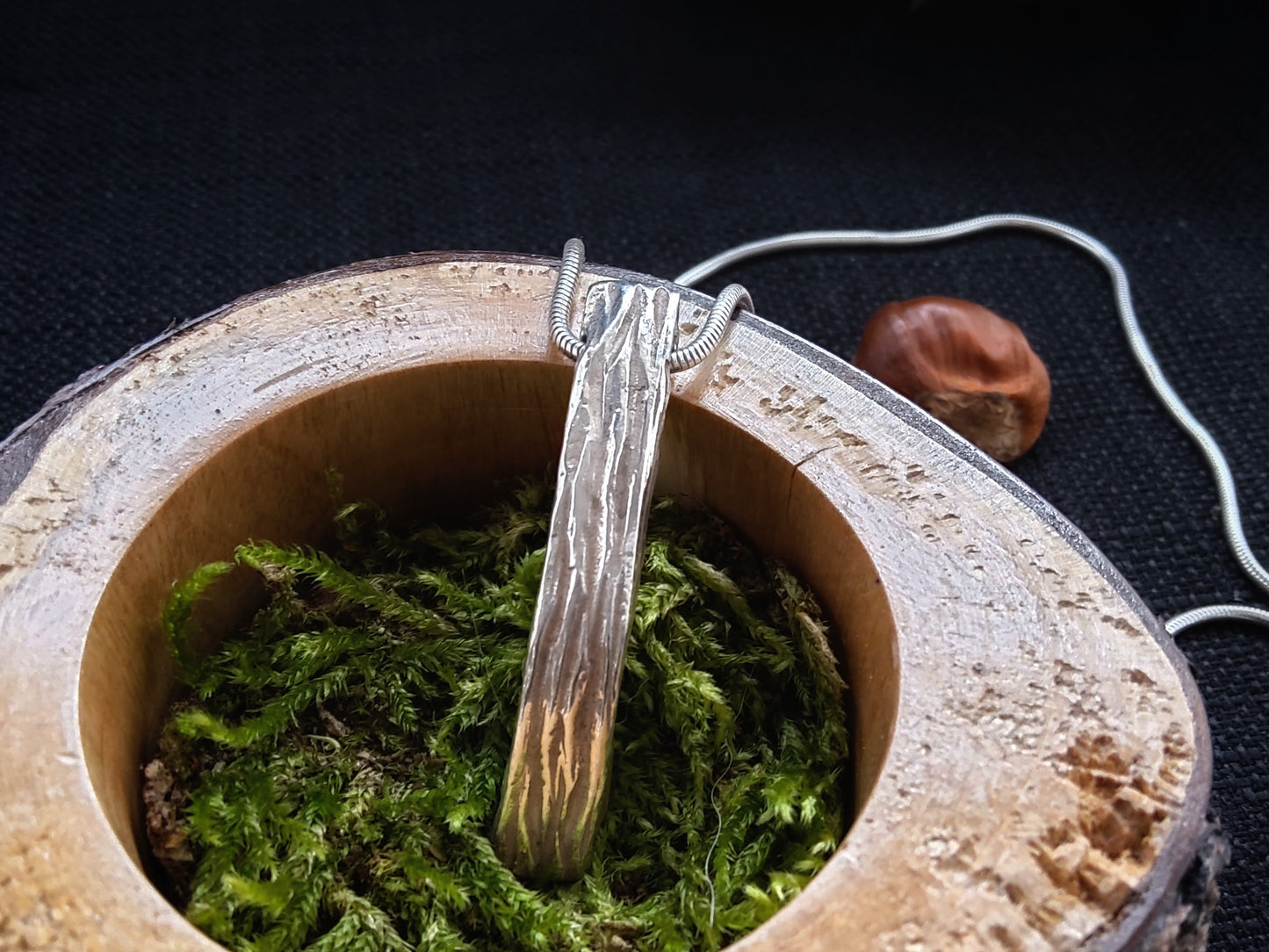 Oxidised Sterling Silver chunky Quarry Wood pendant with tree bark texture sitting in a wooden box with moss by Kara Jewellery by Charlotte
