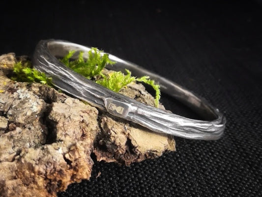 Sterling silver, textured men's ring on a log with moss