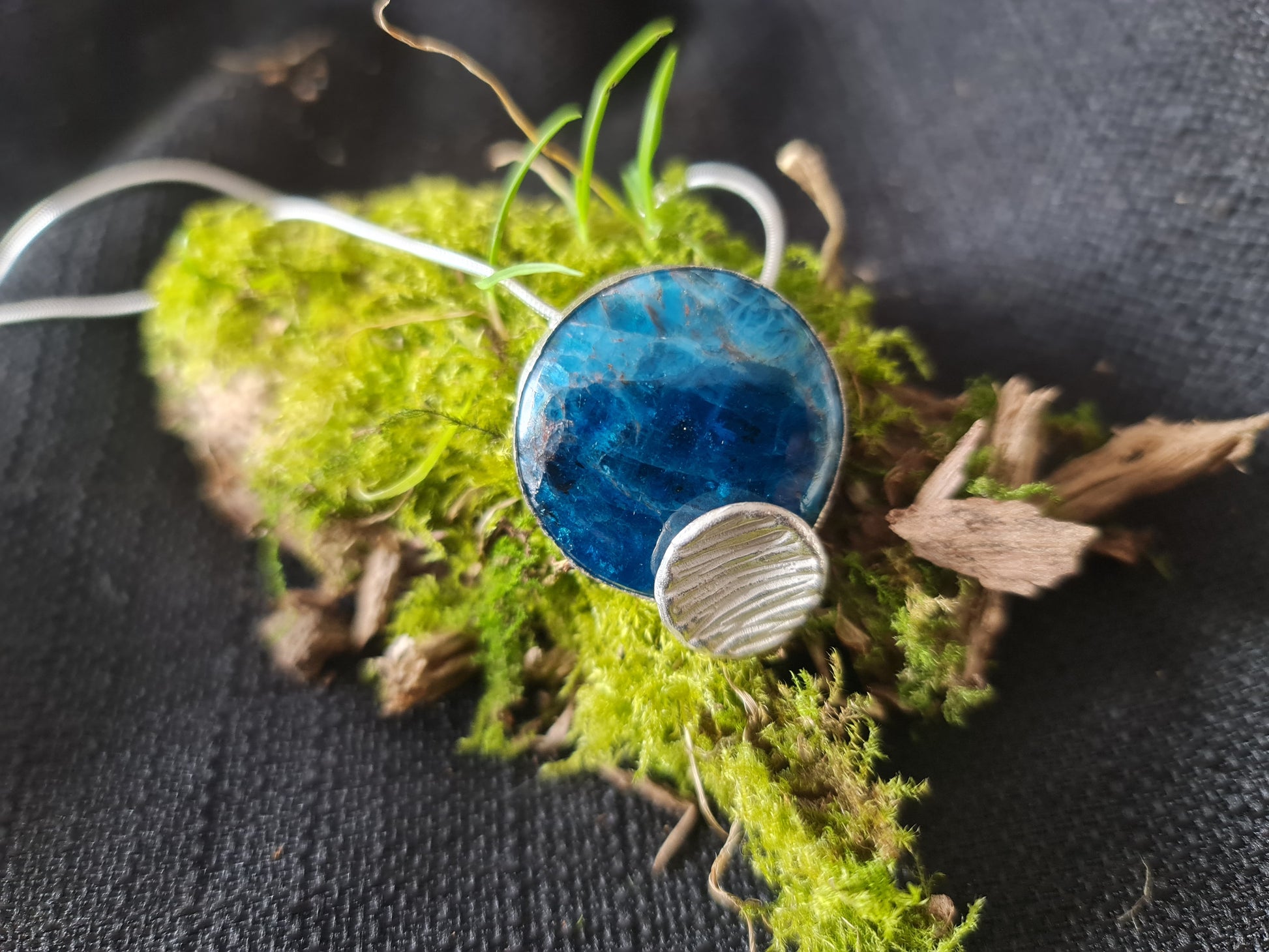 3 cm apatite cabochon with a 1 cm sterling silver concave circle pendant shown on moss as it is inpired by nature