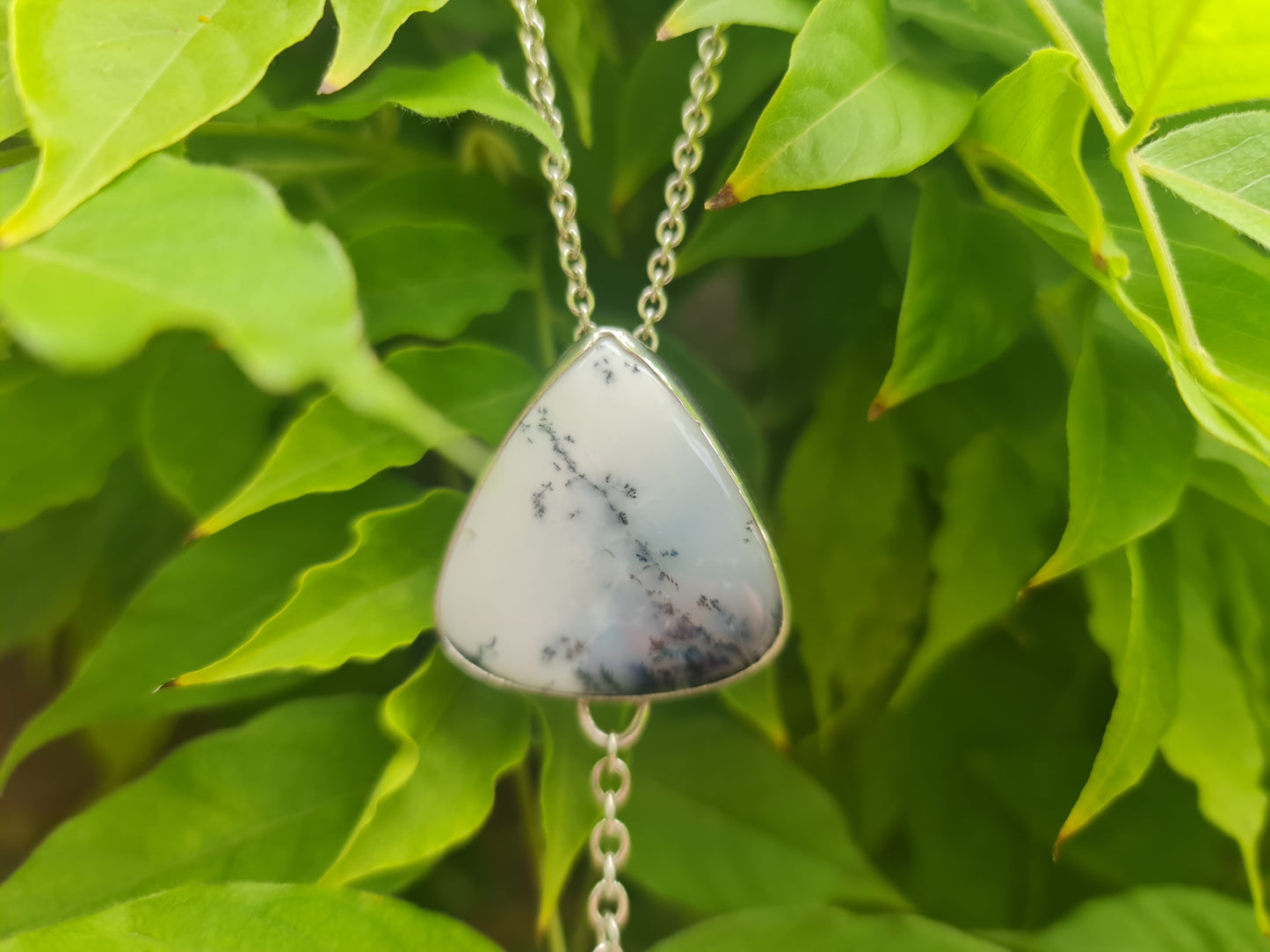 Close up picture of this stunning white and grey dendritic opal which has been bezel set and combined with a textured circle for a stunning pendant.