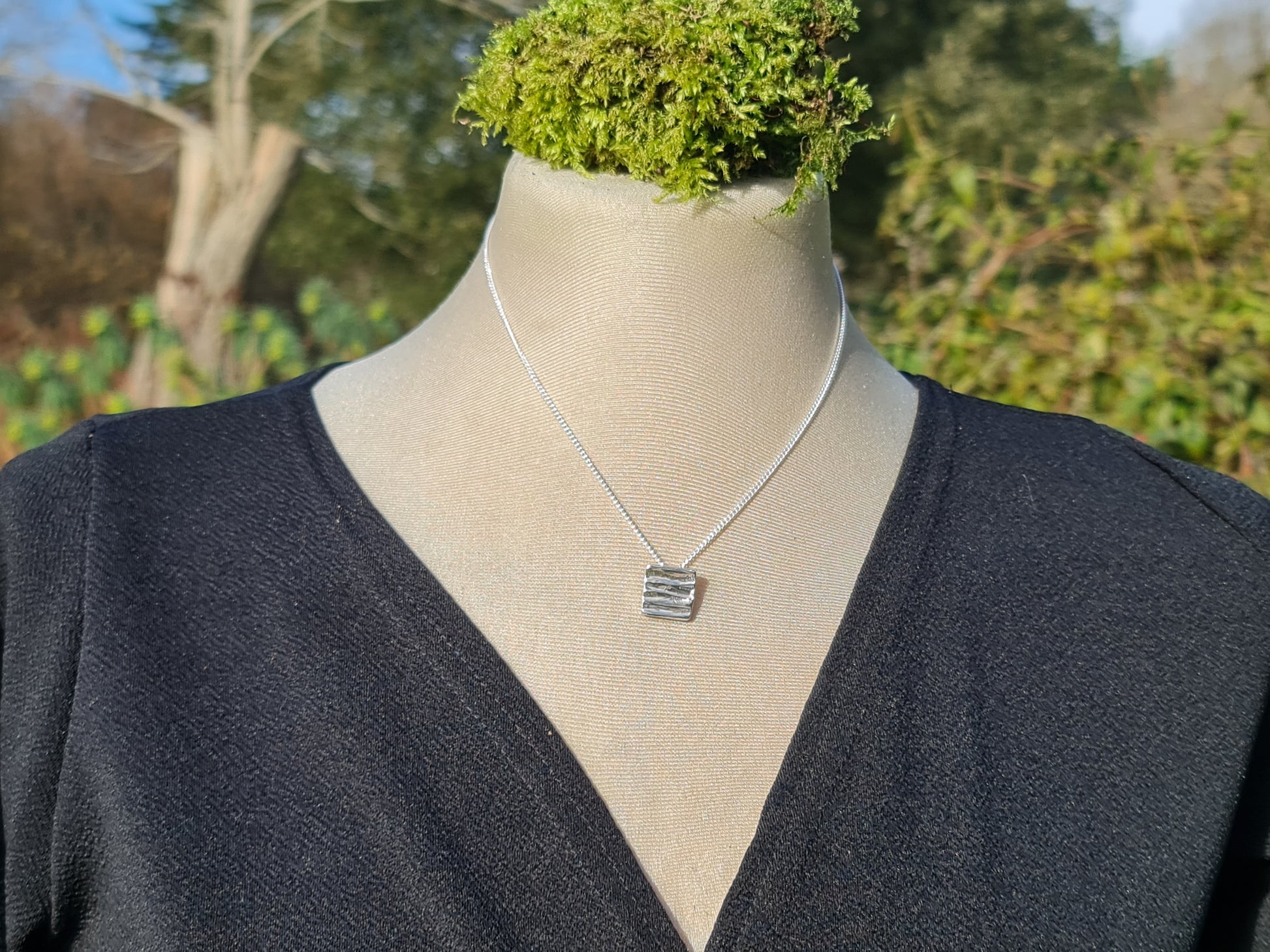 Sterling silver hand crafted pendant with a tree bark texture on a silver chain.